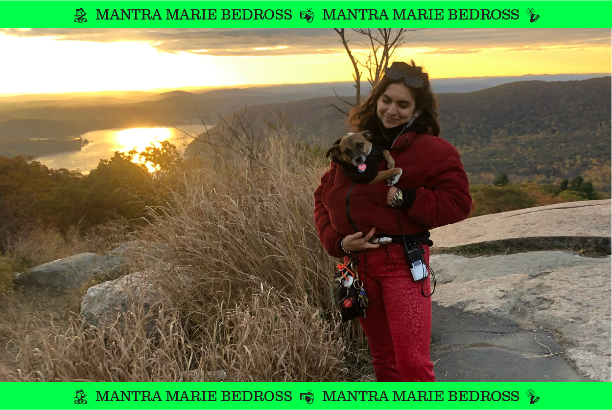 An image of Mantra Marie Bedross holding a dog overlooking a valley.