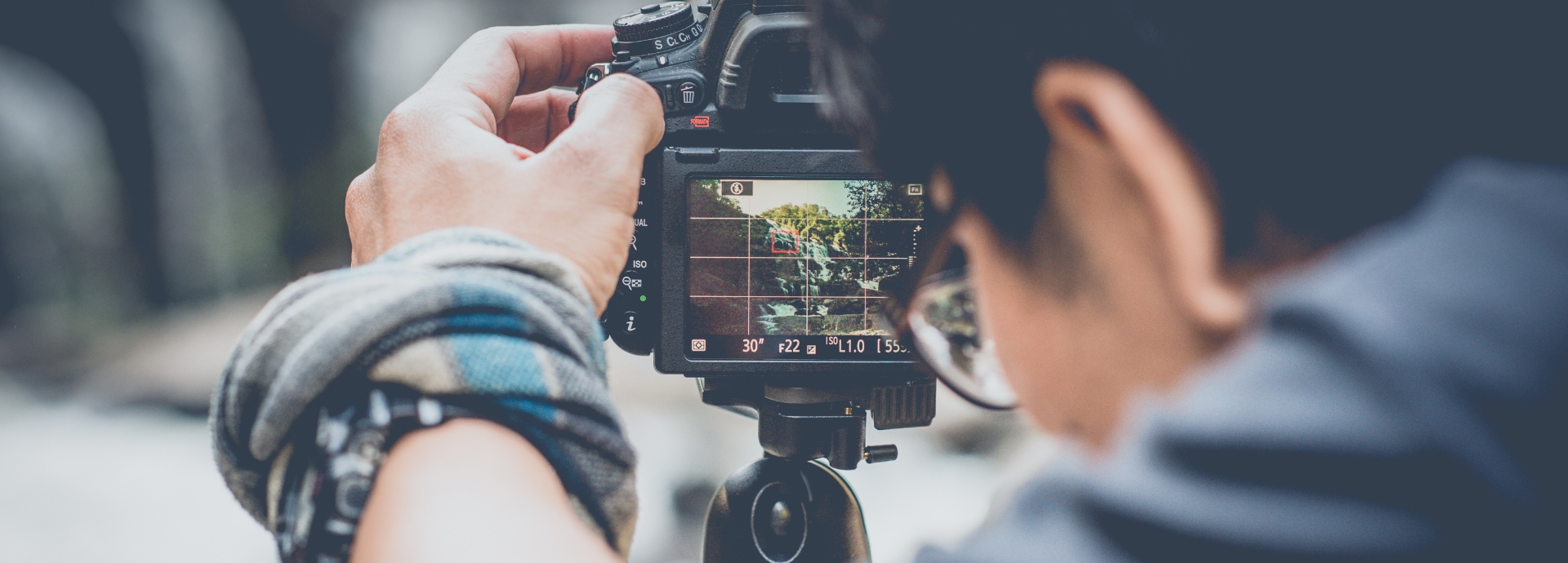 Photo of a man focusing a camera on a tripod
